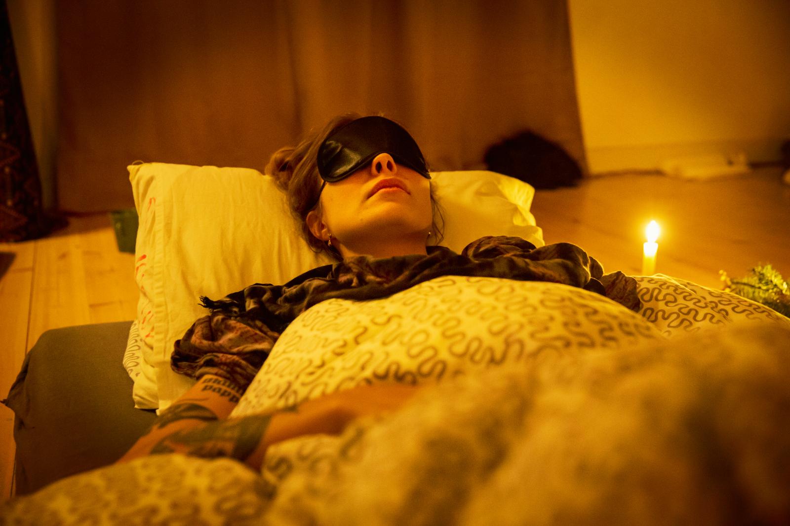 A client resting with an eye mask by candlelight during a session